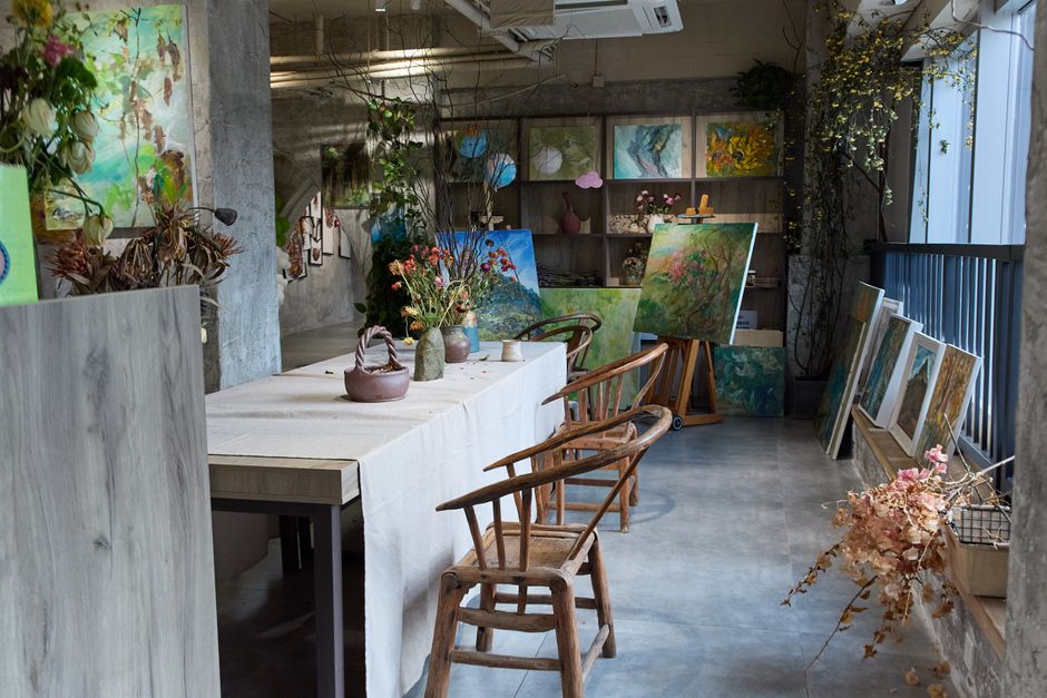 Bright and inviting art studio filled with colorful paintings and floral arrangements.